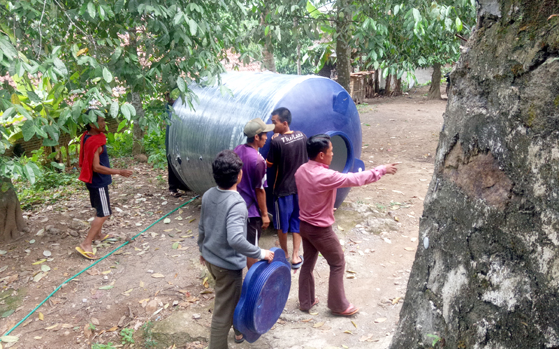 Indonesian men installing water tank
