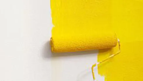 Yellow paint roller painting wall